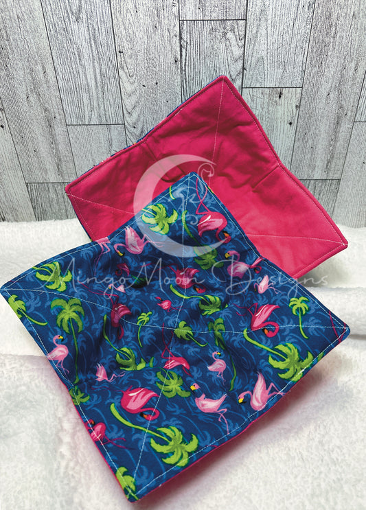Bowl cozy with flamingo print on blue background with green palms and blue palms. Reverse side is fuchsia pink solid color.