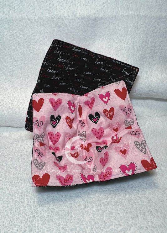 Pink fabric with many different prints of hearts on one side and black fabric with the word love written in different colors for the other side. 